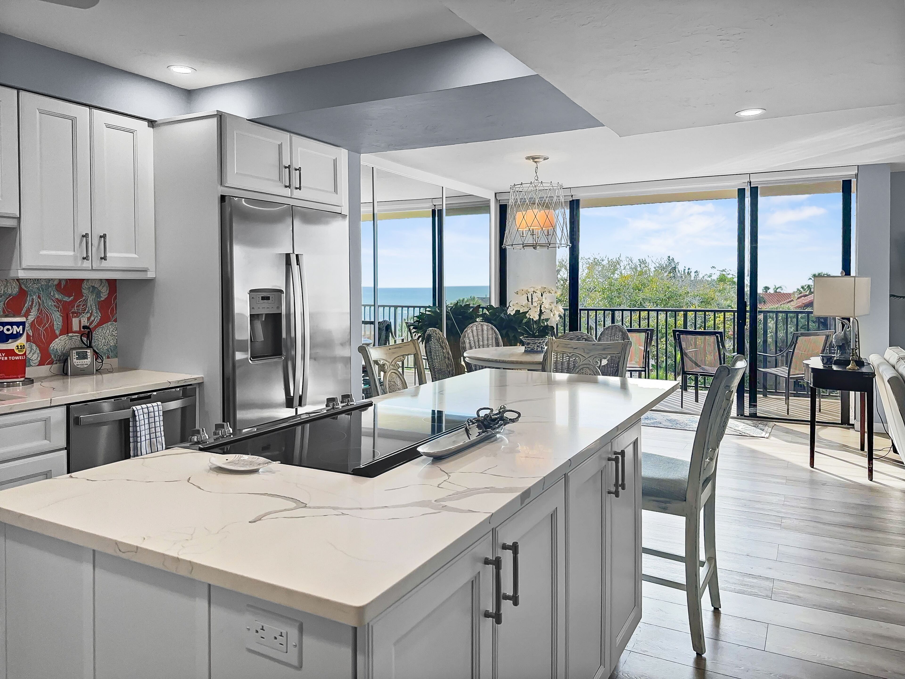 Kitchen with white cabinetry, island countertop, and large windows with gulf views