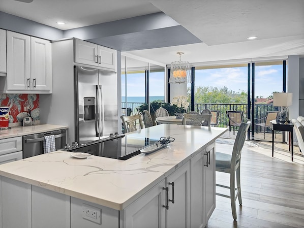 Kitchen with white cabinetry, island countertop, and large windows with gulf views