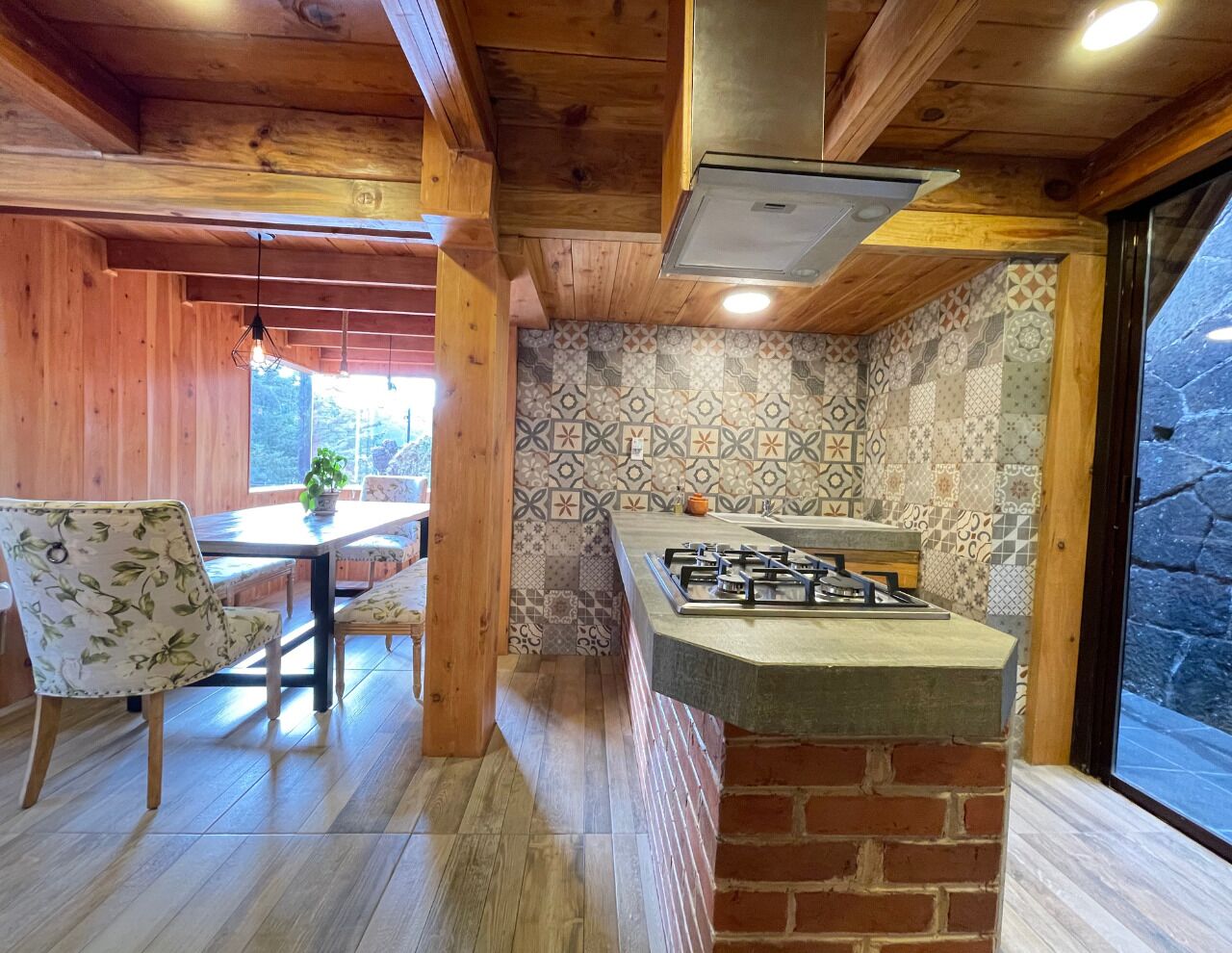 A kitchen with a gas stove, wooden ceiling, and patterned tiles.