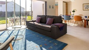 A modern living room with a grey sofa, colorful throw pillows, a glass coffee table, and a blue patterned rug. - La Tingère by Interhome (Pornic)