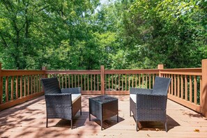 Une terrasse en bois avec des chaises en osier et une table en verre.