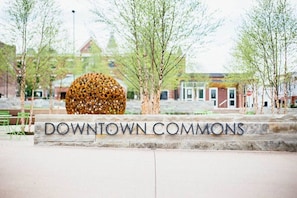 Schild mit der Aufschrift 'DOWNTOWN COMMONS', im Hintergrund eine Kugelplastik und Bäume.