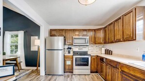 Una cocina con armarios de madera, un refrigerador, un microondas, un horno y un lavamanos.