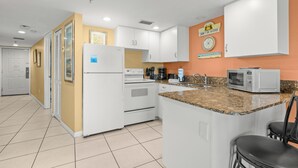 A kitchen with white cabinets, a built-in oven, a microwave, and a granite countertop.