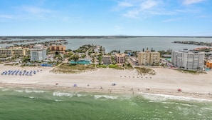 An aerial view of a coastal resort with beachfront properties, a sandy beach, and a marina.