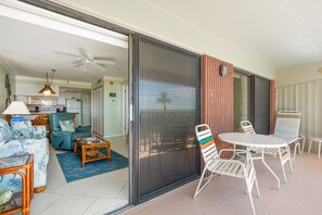 A living room with a sofa, coffee table, and a dining area with chairs and a table. - Gulf Beach 202 - Gulf Views & Sunset Magic from Your Private Balcony (St Pete Beach)