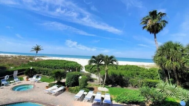 A poolside area with lounge chairs and a view of the beach.