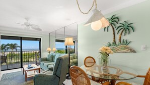 A spacious living area with a balcony, a dining table, and a sofa.