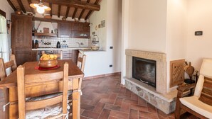 A rustic kitchen with wooden beams, a stone fireplace, and a dining area with a wooden table and chairs. - Dimora del Re by Interhome (Sassofortino)