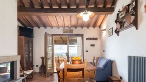 A rustic dining area with a wooden table and chairs, a fireplace, and a view through an open door. - Dimora del Re by Interhome (Sassofortino)