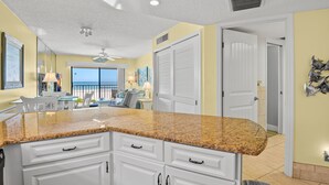A kitchen with white cabinets, granite countertops, and a view to the outside.
