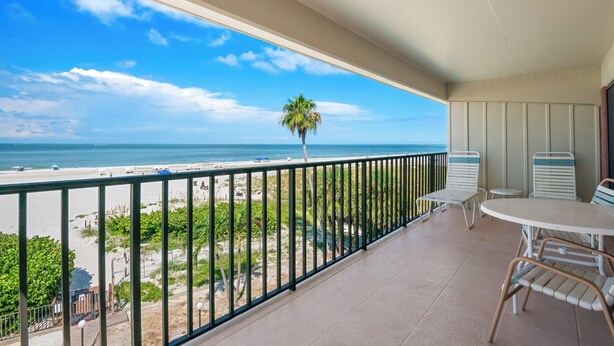 A balcony with a view of the beach and ocean.