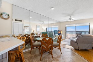 A spacious living area with a dining table, chairs, and a sofa. - 🌊 Panoramic Gulf Views & Soothing Coastal Vibes (St Pete Beach)