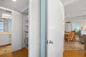 A modern interior with a white closet, a dining area with wicker chairs, and a view of the outside. - 🌊 Panoramic Gulf Views & Soothing Coastal Vibes (St Pete Beach)