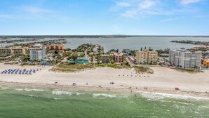 An aerial view of a coastal resort with beachfront properties, a sandy beach, and a marina.