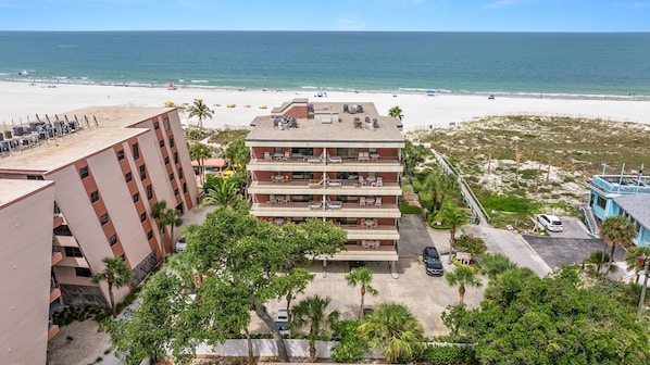 A hotel with multiple floors, outdoor seating, and a view of the beach.