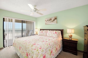 A bedroom with a bed, a nightstand, a dresser, a ceiling fan, and a window with blinds.