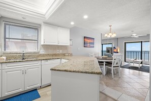 Une cuisine moderne avec des meubles blancs, des plans de travail en granit et un îlot central.