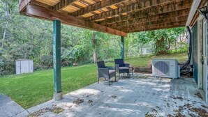 Une terrasse couverte avec des chaises, un appareil de climatisation et un plafond en bois.