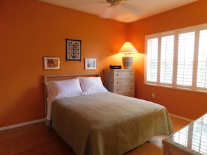 A bedroom with a bed, a dresser, a lamp, and a window with blinds. - Beachwalk 2/2 Ground floor, handicap accessible (Fort Myers)