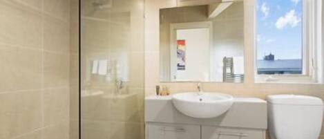 Un baño moderno con cabina de ducha de vidrio, un lavabo con espejo y un inodoro.