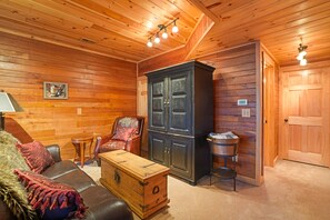 A cozy room with wooden walls, a leather sofa, a cabinet, and a small table.