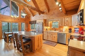 L’intérieur d’une cabane en bois comprend une grande table à manger, un coin cuisine et des placards intégrés.