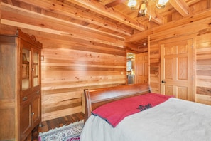 Ein Zimmer mit Holzwänden, einem Bett, einem Schrank und einer Tür.