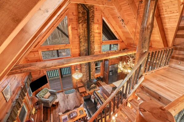 Eine geräumige Loft-Hütte mit hoher Decke, freiliegenden Holzbalken und einem Steinkamin.