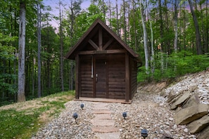 Eine Holzhütte mit Satteldach, umgeben von einem Wald.