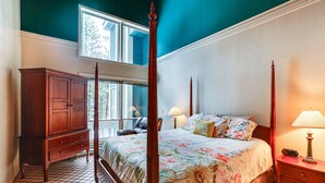 Een slaapkamer met een hemelbed, een houten dressoir en een nachtkastje met een lamp.