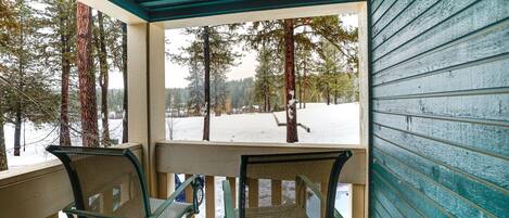 A covered porch with two chairs and a view of a snowy landscape.