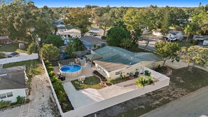 A residential property with a swimming pool, a covered patio, and a fenced yard.