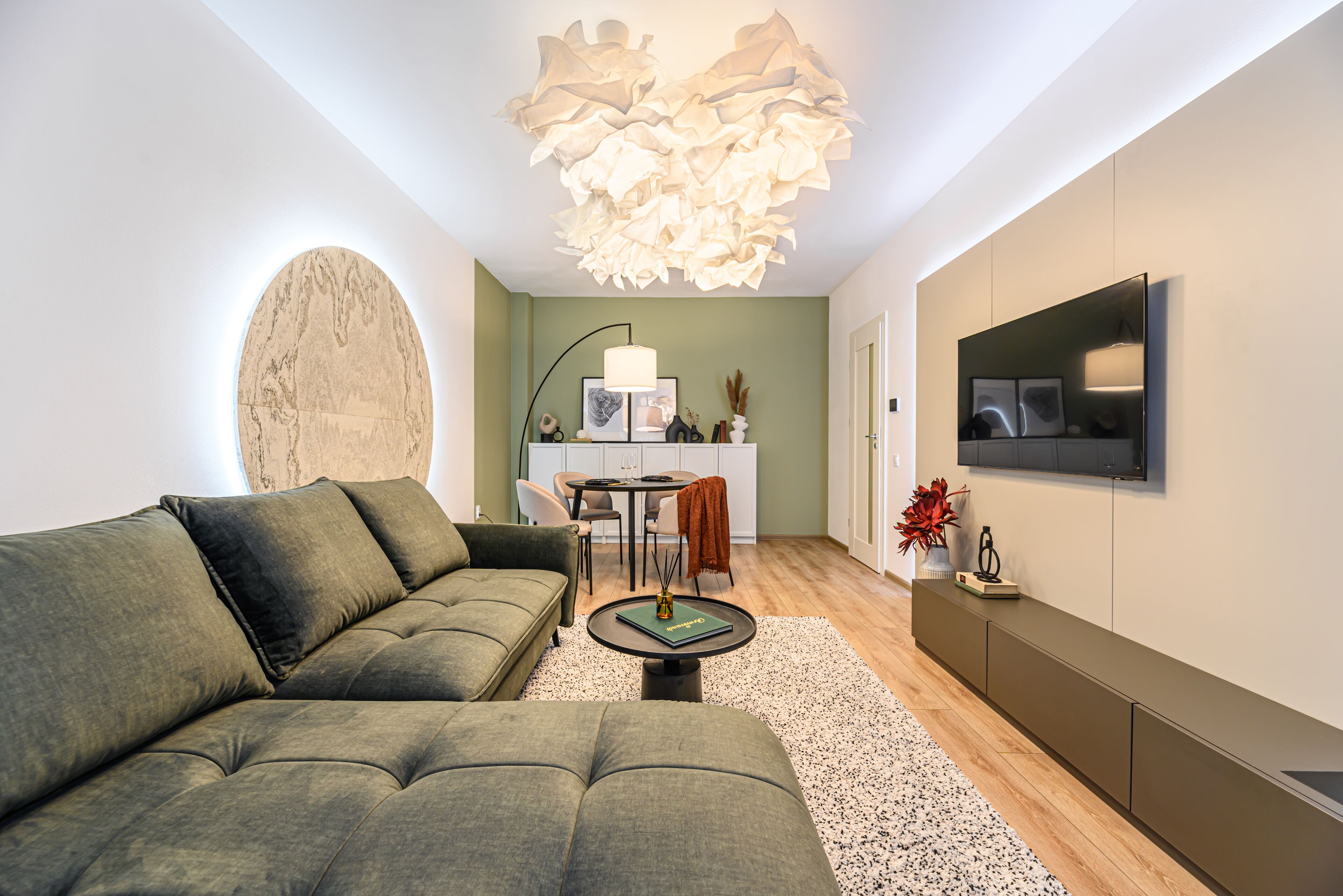 Una sala de estar moderna con un sofá modular, una mesa redonda de centro y un comedor con mesa y sillas.