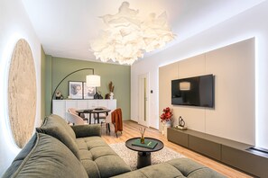 Un soggiorno moderno con divano, tavolino, televisore e una lampada a sospensione particolare.