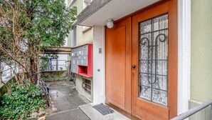 A wooden door with a glass panel, a mailbox, and a bicycle parked outside. - Superb St. Johann 1BR w/ Storage Room, close to Station, by Blueground (Basel)