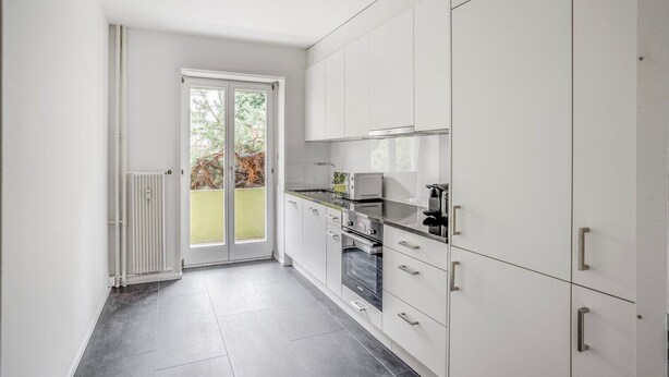 A modern kitchen with white cabinets, a black countertop, and a built-in oven. - Superb St. Johann 1BR w/ Storage Room, close to Station, by Blueground (Basel)