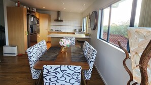 A modern kitchen with a central island, wooden flooring, and a dining area with patterned chairs and a wooden table.