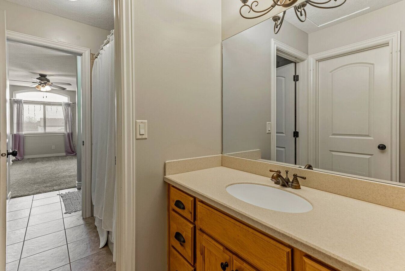 A bathroom with a white sink, wooden vanity, and a large mirror.