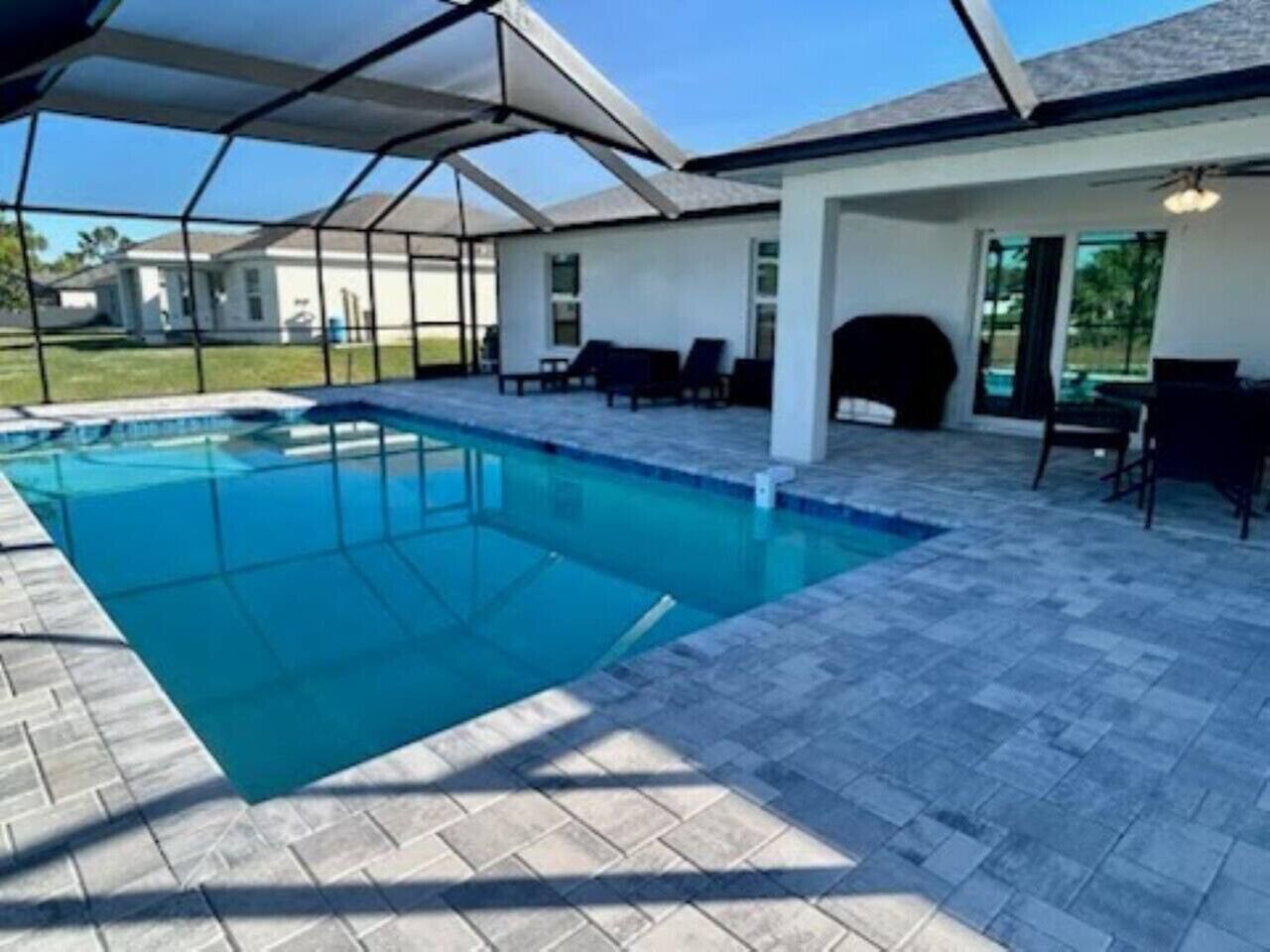 Ein Swimmingpool mit überdachter Terrasse, Liegestühlen und freiem Blick auf die umliegende Landschaft.