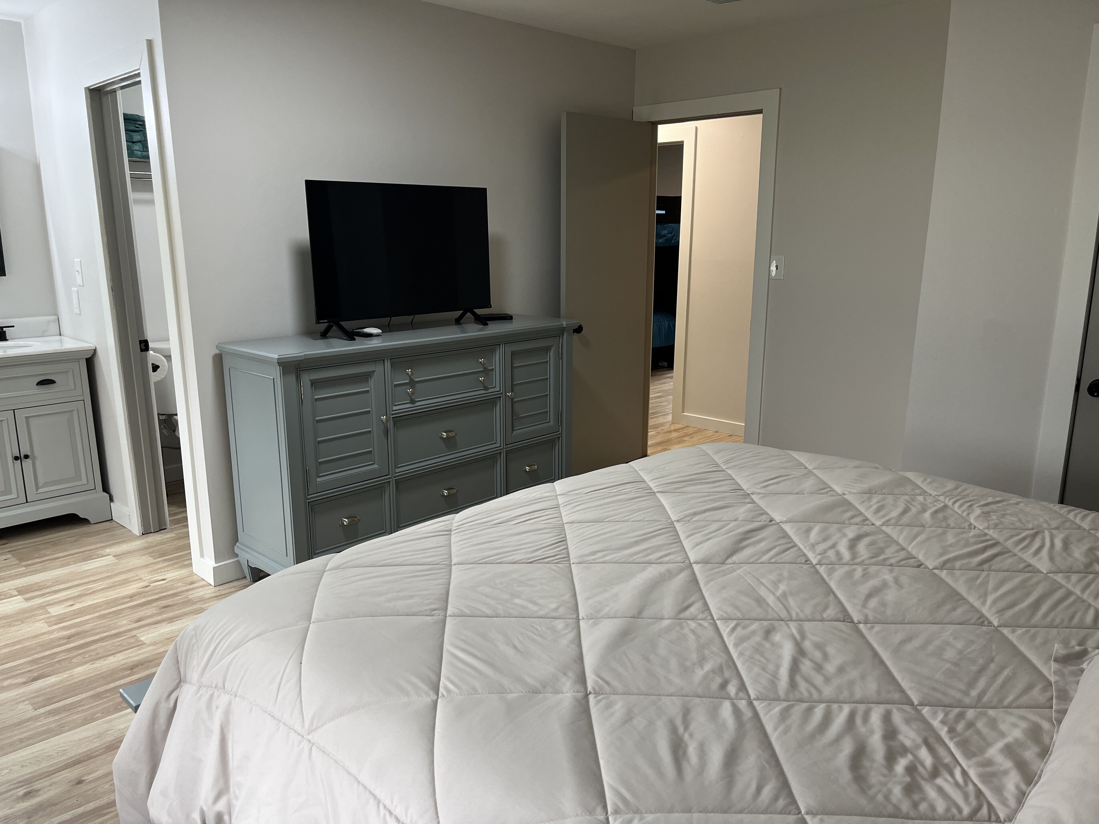 A bedroom with a bed, a dresser, and a television.