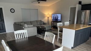 Une cuisine moderne avec un îlot en bois, des chaises blanches et une table à manger.