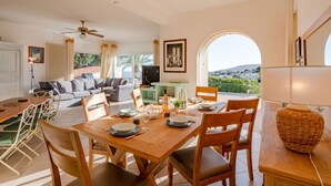 A spacious living area with a dining table set for four, a sofa, and a television. - Les Chèvrefeuilles by Interhome (Saint Aygulf)