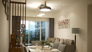 A modern dining area with a wooden table set for four, a sofa, and a floor lamp. - Great location - 2BR Apartment in Senayan, Jakarta (Daerah Khusus Ibukota Jakarta)