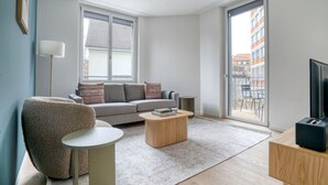 En moderne stue med en grå sofa, et rundt sofabord og en blød lænestol.