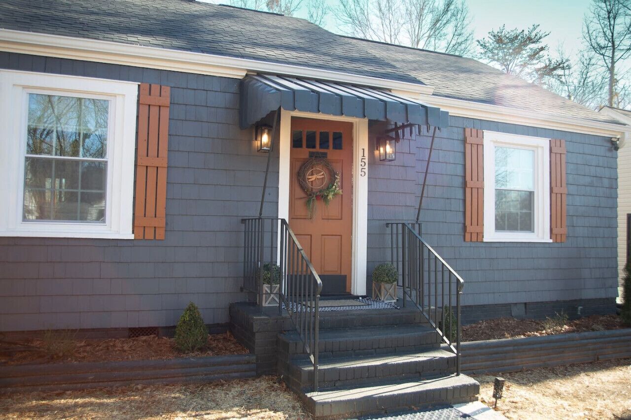 A house with a front porch, a wooden door, and a number '155' on the wall.
