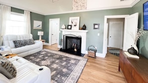 Un salon spacieux avec un canapé blanc, une cheminée et un grand tapis.