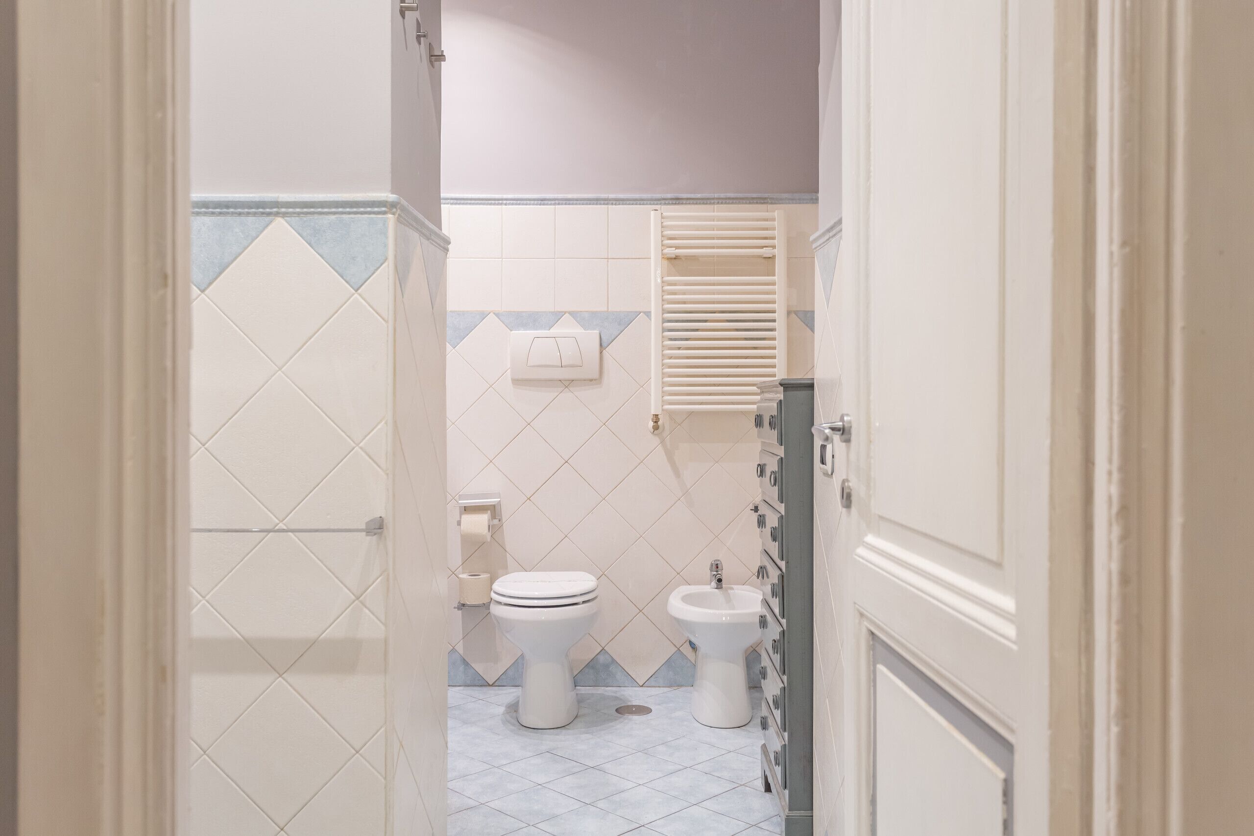 A bathroom with a toilet, bidet, and towel rack.
