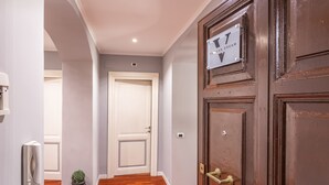 A hallway with a wooden door, a potted plant, and a sign on the door.