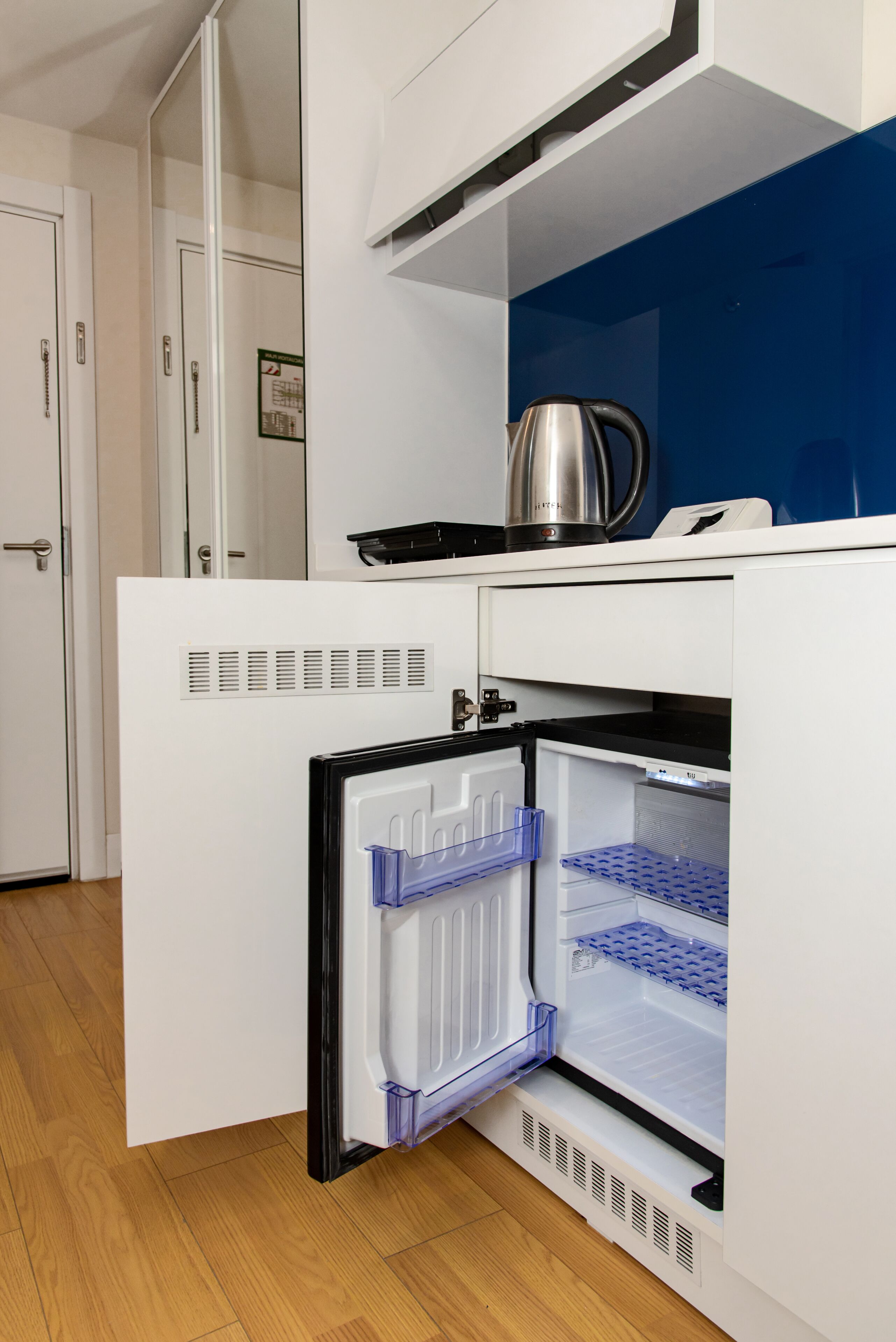 Una cocina compacta con refrigerador incorporado, hervidor y microondas.